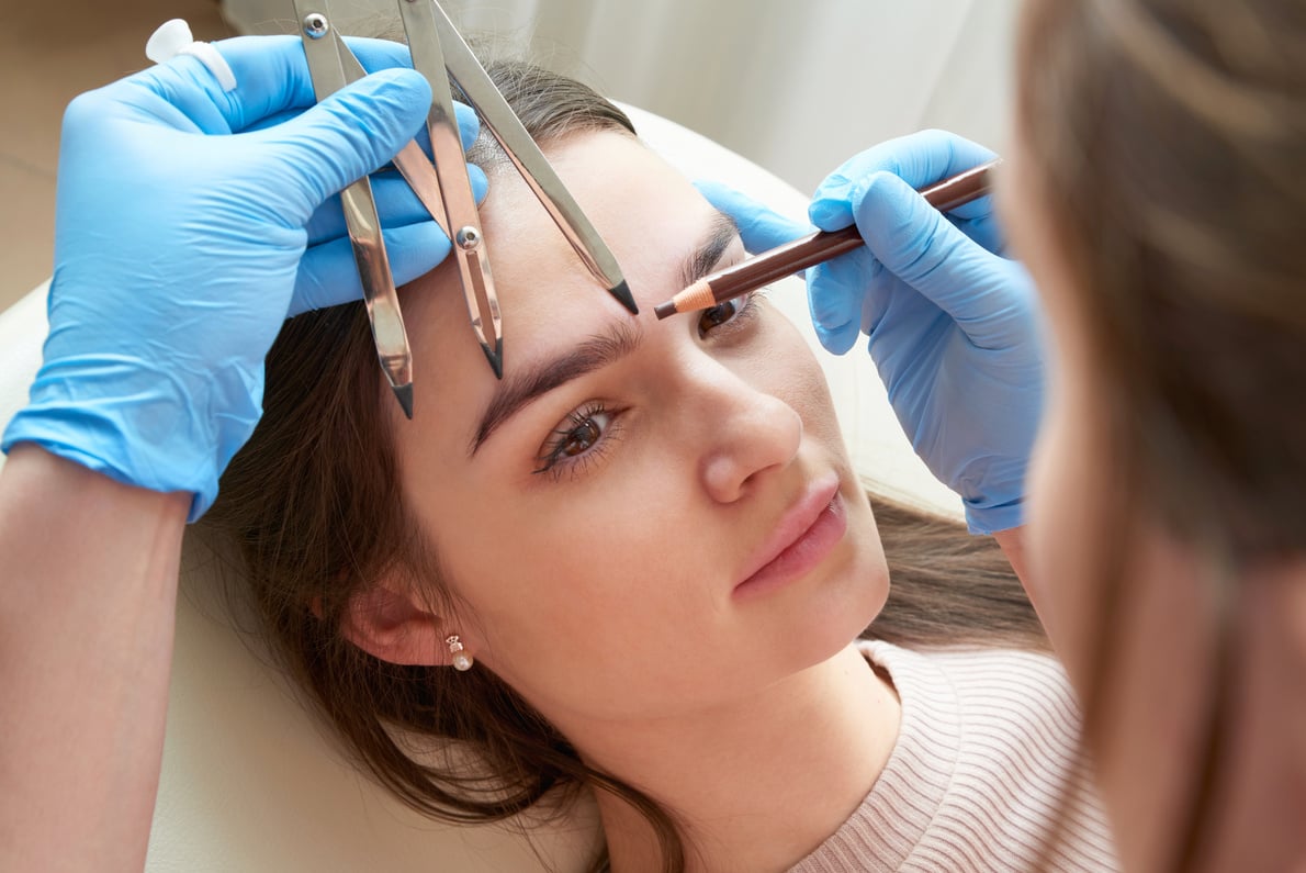 Cosmetologist measures the proportions of the eyebrows with the ruler